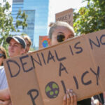 "Denial is not a policy" protest sign